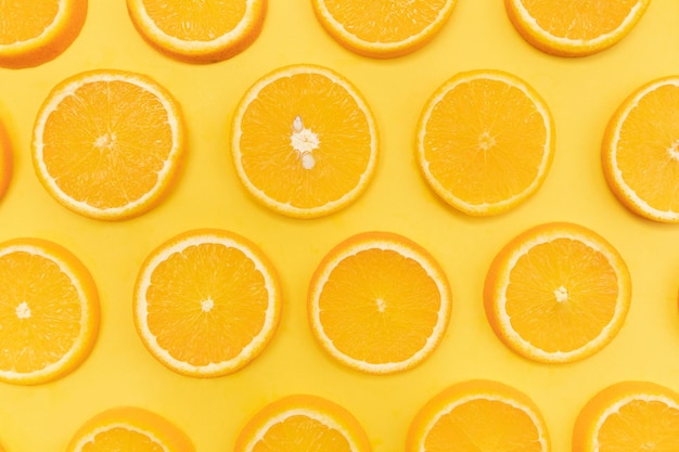 Vista superior de naranjas en rodajas sobre un fondo amarillo