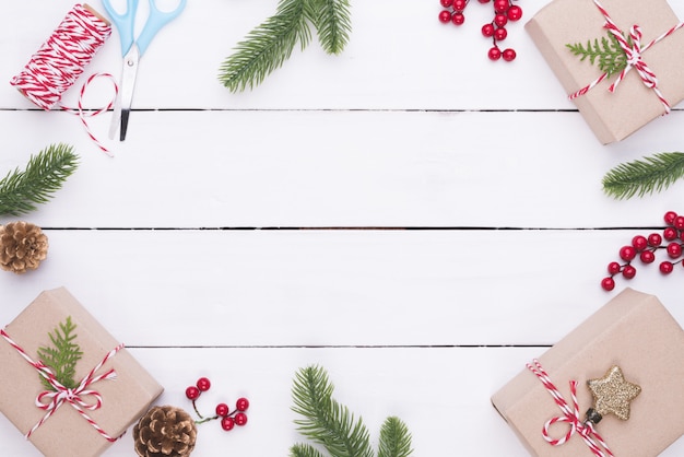 Vista superior de Navidad de caja de regalo con ramas de abeto, conos de pino, bayas rojas en madera blanca