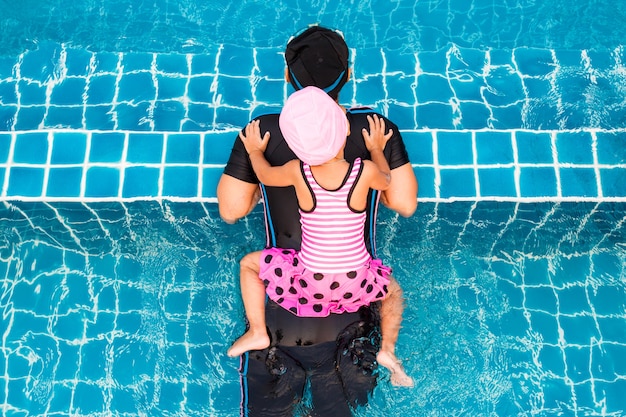 Vista superior de la niña nadando con la madre en la piscina