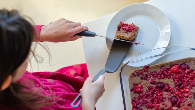 Foto vista superior de una niña que sirve un saludable postre vegano de chocolate con frambuesa