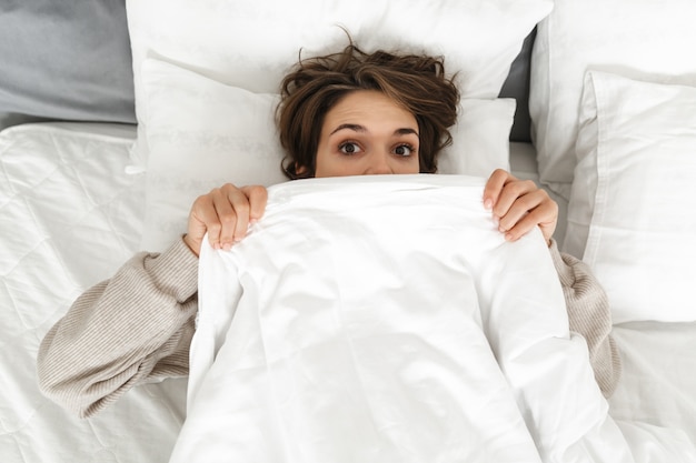 Vista superior de una niña sonriente relajante en la cama por la mañana