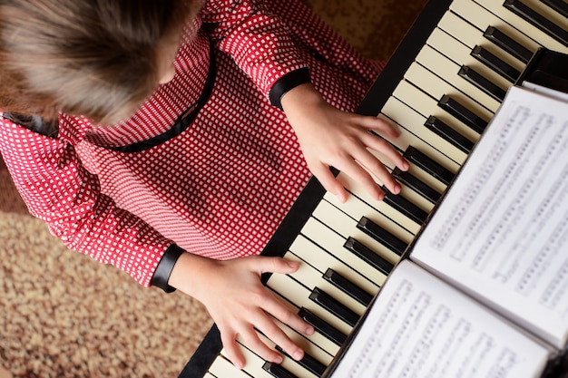 Vista superior de una niña tocando el piano en casa