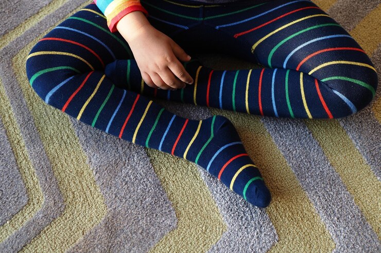 Foto vista superior del niño con calcetines de rayas de colores sentado en la alfombra