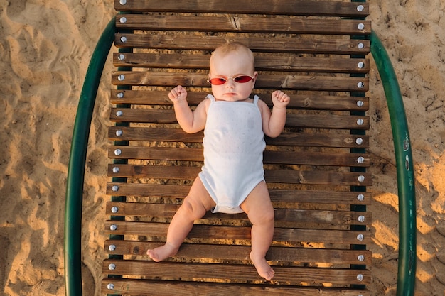 Vista superior de un niño feliz con gafas acostado en una tumbona de madera