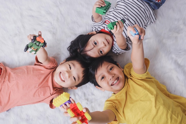 Vista superior de niños felices mostrando sus juguetes sobre fondo blanco.