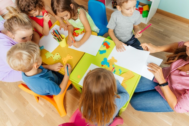 Vista superior de niños de jardín de infantes durante la lección de arte