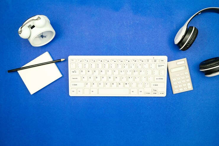 Foto vista superior de los objetos de negocio teclado, ratón, auriculares, papeleo con lápiz y reloj de alarma sobre fondo de papel azul espacio de copia plana mínima para el fondo empresarial y el sitio web.