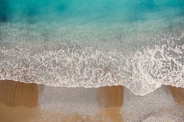 Vista superior de la orilla del mar con agua azul y una playa de arena Vista aérea del mar de la tierra media con costa Hermoso mar tropical en la temporada de verano tomada desde un dron