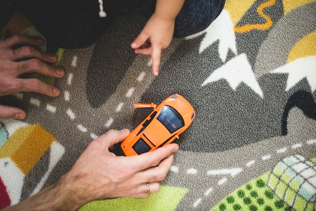 Vista superior de padre e hijo jugando con un coche naranja