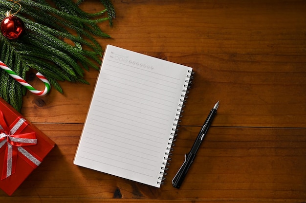 Vista superior Página vazia do caderno em branco e caneta na mesa de madeira com enfeites de Natal