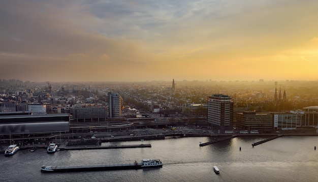 Vista superior del paisaje urbano de Amsterdam al atardecer. Río con barcos, barcos, estación central. Turismo de holandeses.