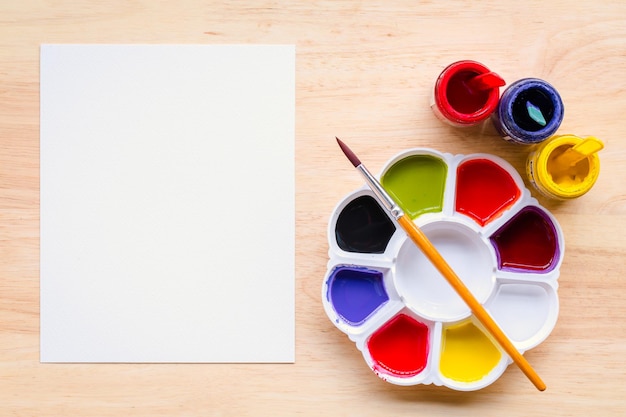 Foto vista superior de la paleta de pinceles y pinturas de acuarela con imagen de papel blanco con espacio de copia y para agregar mensaje de textoxa