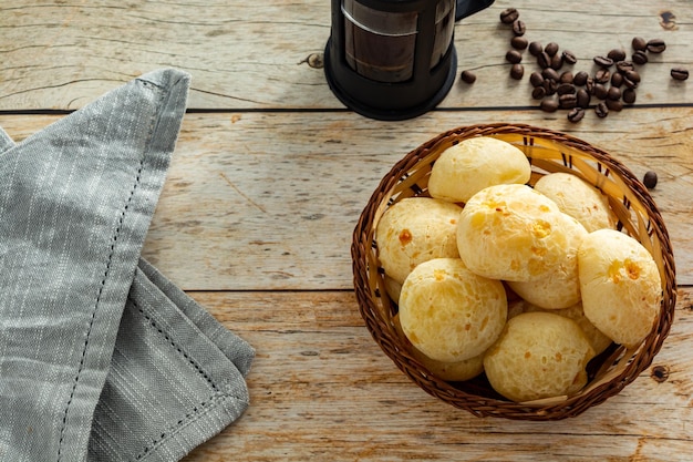 Vista superior de pan de queso brasileño o 'pao de queijo' con cafetera de prensa francesa y granos de café sobre el espacio de copia de la mesa