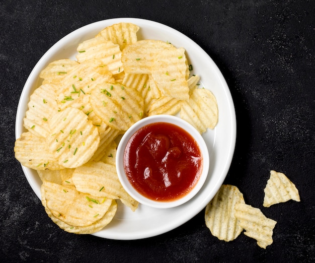 Vista superior de papas fritas en un plato con salsa de tomate