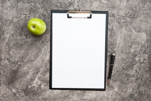 Vista superior de papel en blanco blanco vacío junto a un lápiz y una manzana verde fresca