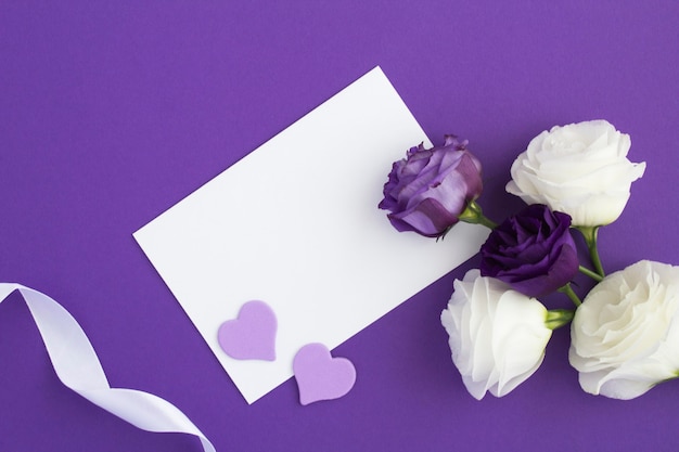 Vista superior del papel blanco vacío para texto y flores en violeta
