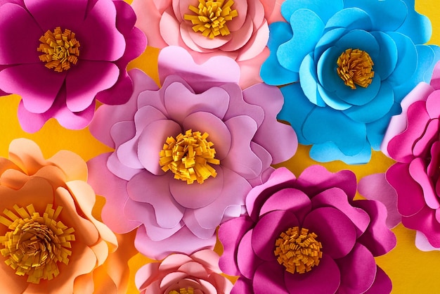Vista superior de papel cortado flores multicolores brillantes sobre fondo amarillo