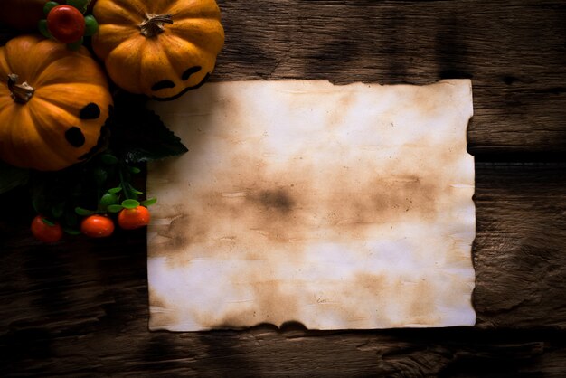 Foto vista superior del papel viejo con las calabazas amarillas del fantasma en el tablero de madera.