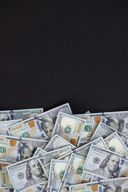 Foto vista superior del paquete de billetes de 100 dólares sobre fondo negro concepto de negocio con espacio de copia