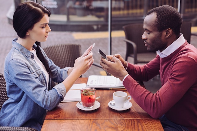 Vista superior de una pareja agradable atractiva enfocada que data mientras sostiene teléfonos