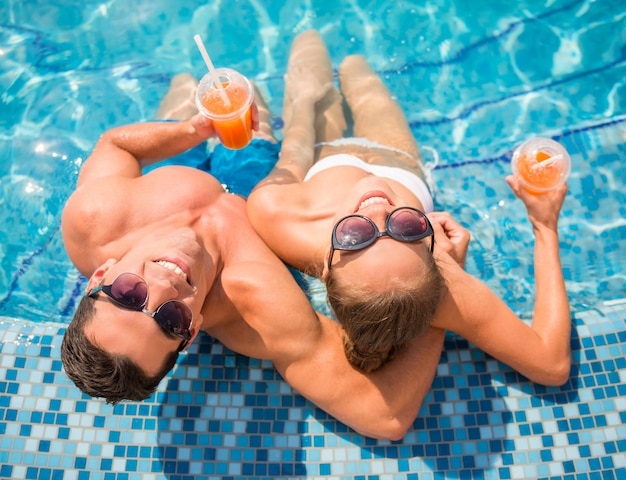 Vista superior de los pares jovenes que se relajan en piscina del centro turístico.