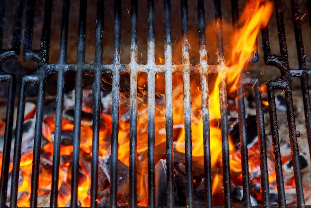 Vista superior de la parrilla de carbón de barbacoa vacía y limpia con llamas de fuego de cerca