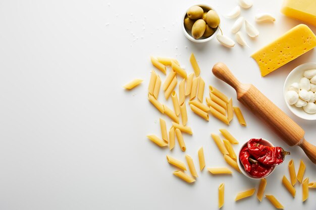 Vista superior de pasta y rodillo con ingredientes sobre fondo blanco.