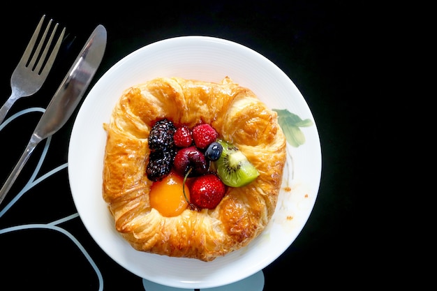 Foto vista superior de la pastelería danesa con frutas remix en el plato blanco.