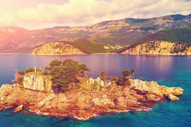 Foto vista superior de la pequeña isla rocosa con un faro en el mar soleado