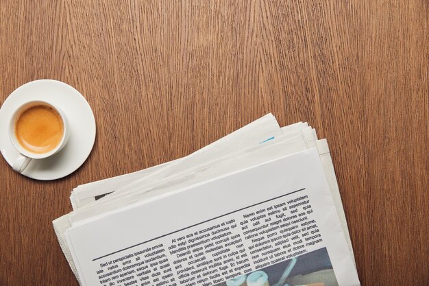vista superior del periódico cerca de la taza de café en la superficie de madera