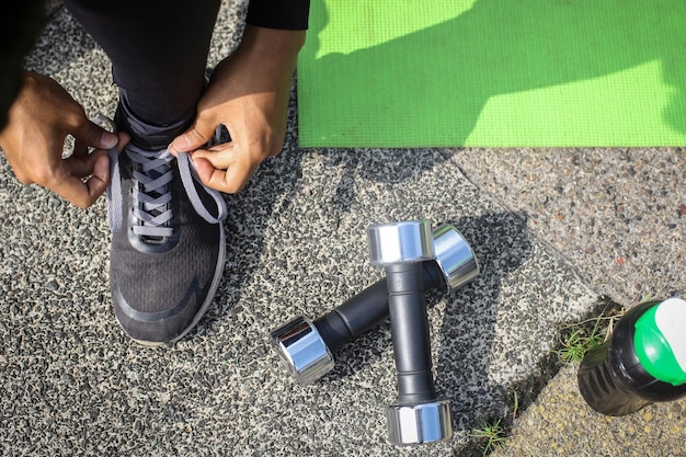 Vista superior de la persona que se ata los zapatos y se prepara para las rutinas de entrenamiento