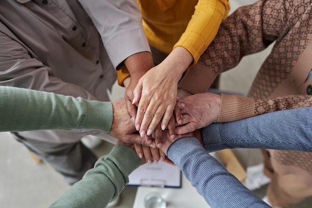 Vista superior de personas mayores apilando las manos en círculo