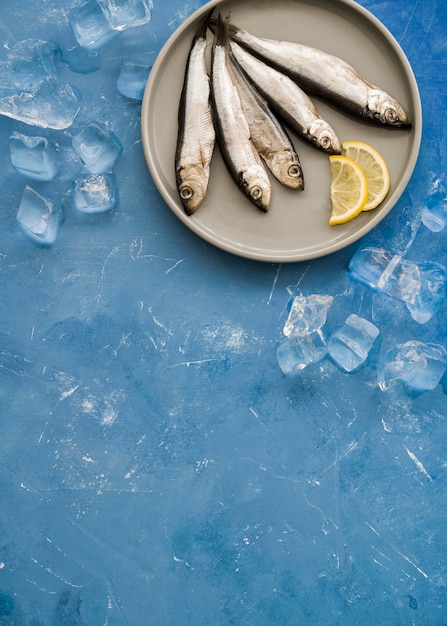 Vista superior de pescado en un plato con rodajas de limón