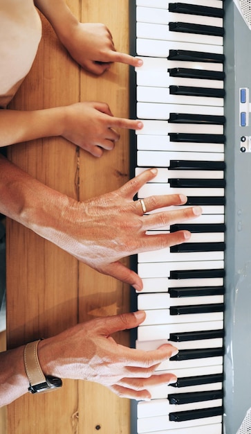Vista superior del piano y manos del niño aprendiendo con el padre en casa jugando o uniéndose Educación para el desarrollo o padres enseñando al niño a tocar instrumentos musicales teclado acústico o eléctrico