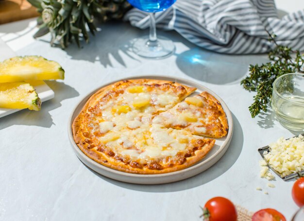 Vista superior de una pieza de forma triangular de deliciosa y sabrosa costra tradicional italiana de jamón delgado y crujiente y pizza de piña estirando el queso desde la mesa