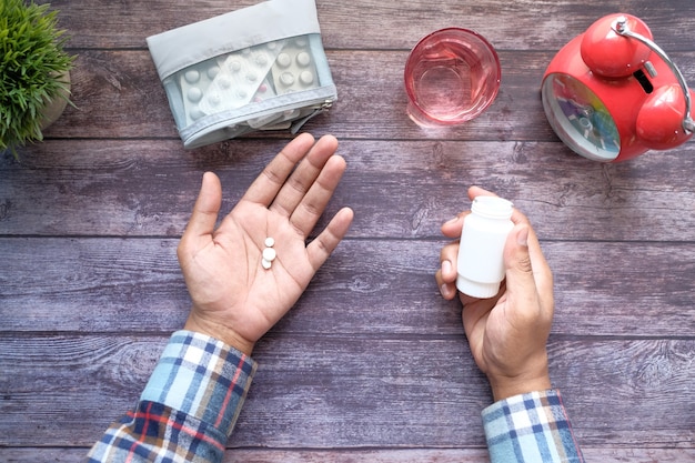 Vista superior de píldoras médicas en la palma de la mano en la mesa