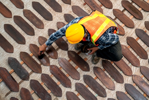 Vista superior de la pintura del trabajador o barniz sobre tabla de madera en el sitio de construcción.
