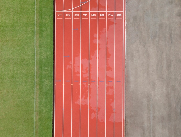 Vista superior de pistas de atletismo rojas y césped de hierba verde