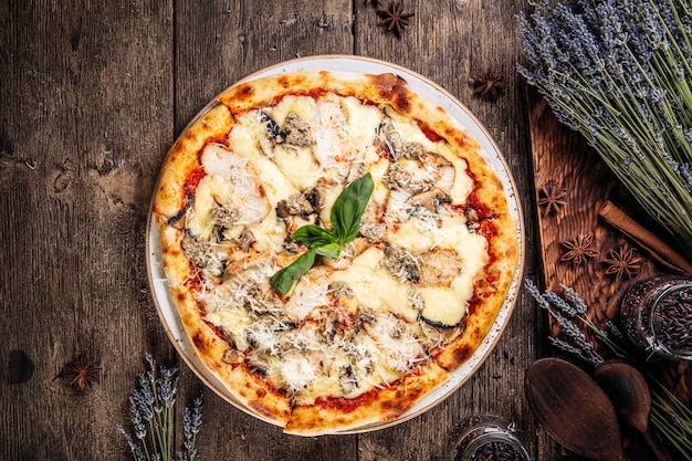 Vista superior de la pizza de masa esponjosa recién horneada italiana con champiñones en la mesa de madera