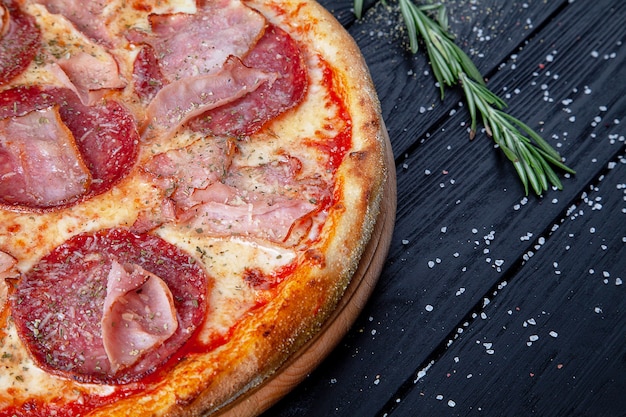 Vista superior pizza con salami, ají picante, jamón y queso sobre fondo de madera oscura. Copiar sapce para el diseño. Fondo de alimentos Cocina italiana. Comida plana