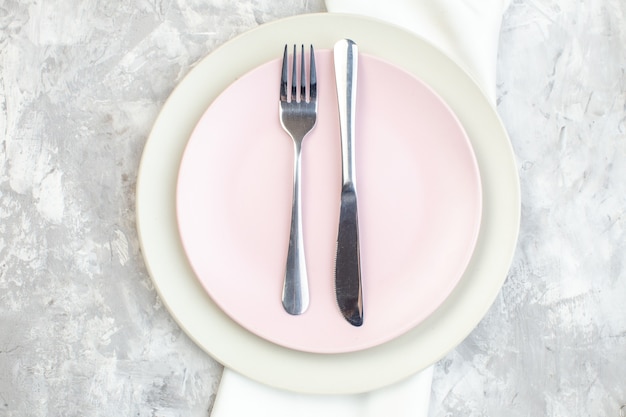 Vista superior de la placa blanca con placa rosa y cubiertos en la superficie de la luz cocina feminidad comida color señoras cristal de alimentos