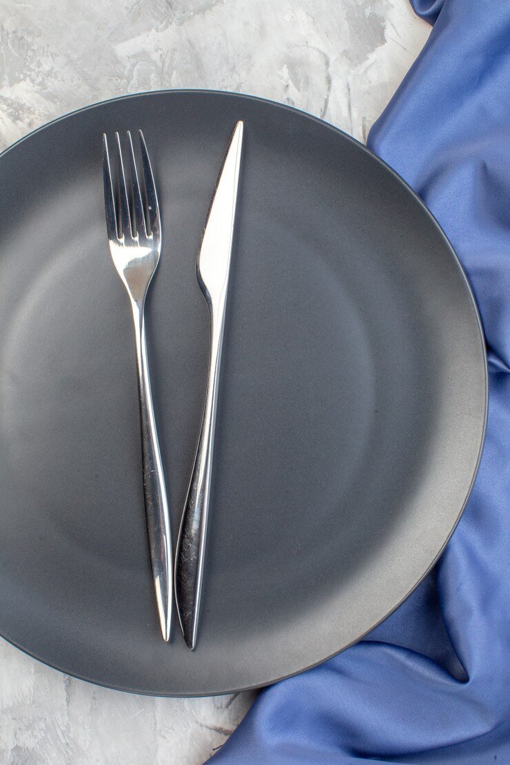 Foto vista superior de la placa oscura con un tenedor y un cuchillo en la superficie de la luz de cristal de cocina señoras feminidad comida de color horizontal