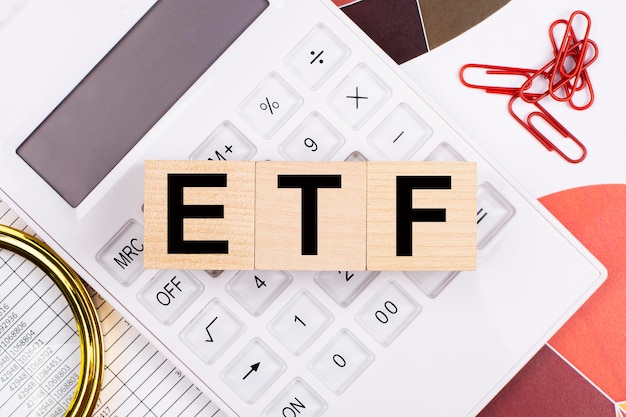 Vista superior plana da mesa de escritório Local de trabalho com calculadora branca lupa clipes de papel vermelho e cubos de madeira com ETF Exchange Traded Funds