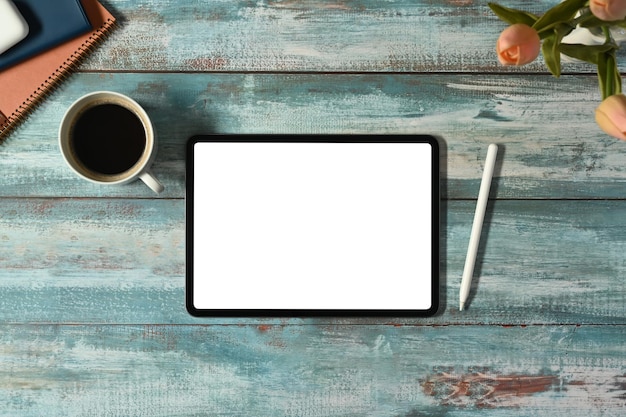 Vista superior plana do tablet digital com xícara de café de tela branca e livros sobre mesa de madeira rústica