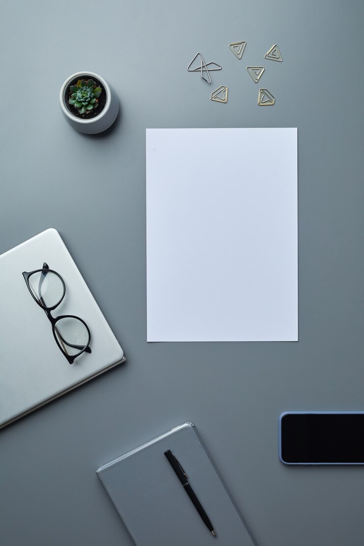 Foto vista superior plana laicos de papel blanco en blanco sobre fondo gris del lugar de trabajo con teléfonos inteligentes y accesorios comerciales,