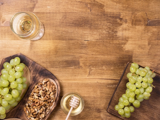 Vista superior plana leiga do pote de mel ao lado de uvas frescas na mesa de madeira. vinho branco vintage. degustação de alimentos. copie o espaço disponível.