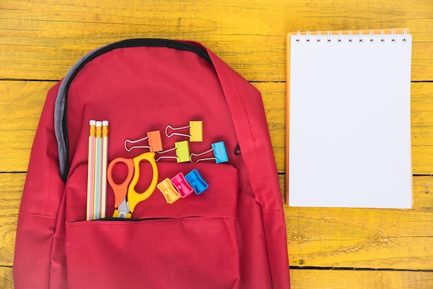 Vista superior plana de mochila escolar roja y herramientas de accesorios para la educación de los niños