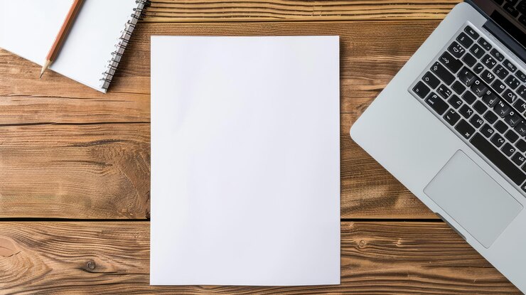 Foto vista superior de una plantilla de modelo de documento en papel de currículum vertical blanco en blanco en una mesa de oficina de madera