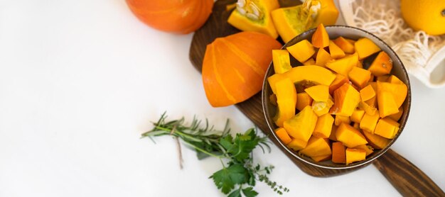 Foto vista superior de un plato con pedazos de calabaza cruda en la mesa de la cocina larga pancarta con espacio de copa concepto de otoño día de acción de gracias