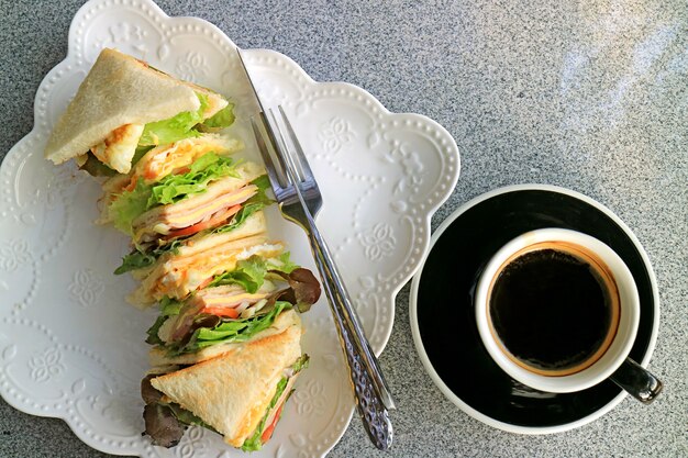 Vista superior de un plato de sándwiches mixtos servidos con una taza de café aromático caliente